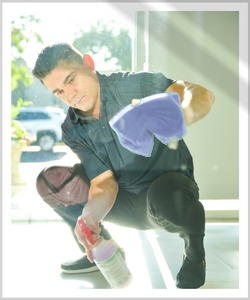 A cleaning franchise owner with Buildingstars cleans glass with a microfiber towel and disinfectant spray. Cleaning can help discourage your employees from resigning.